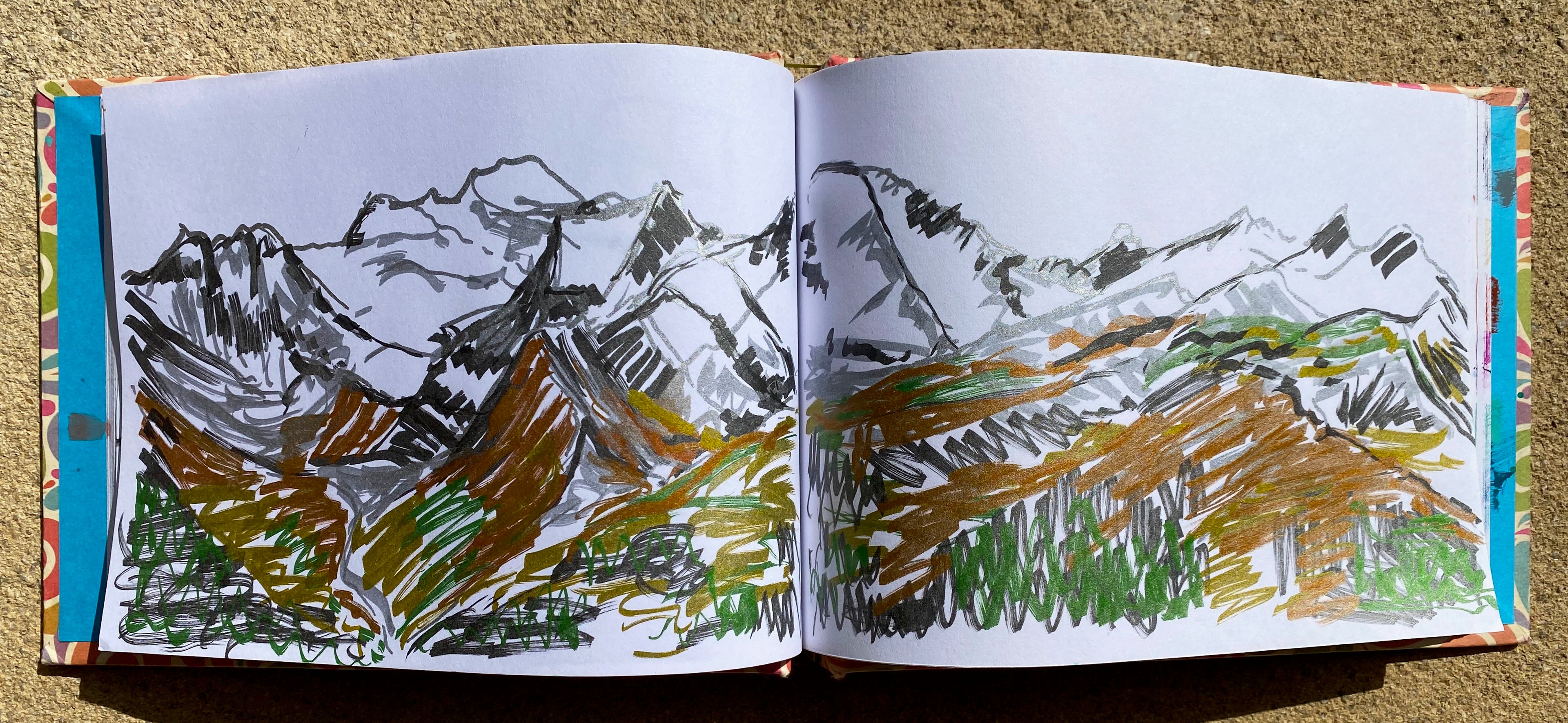 Open book with mountain landscape drawings on a textured surface